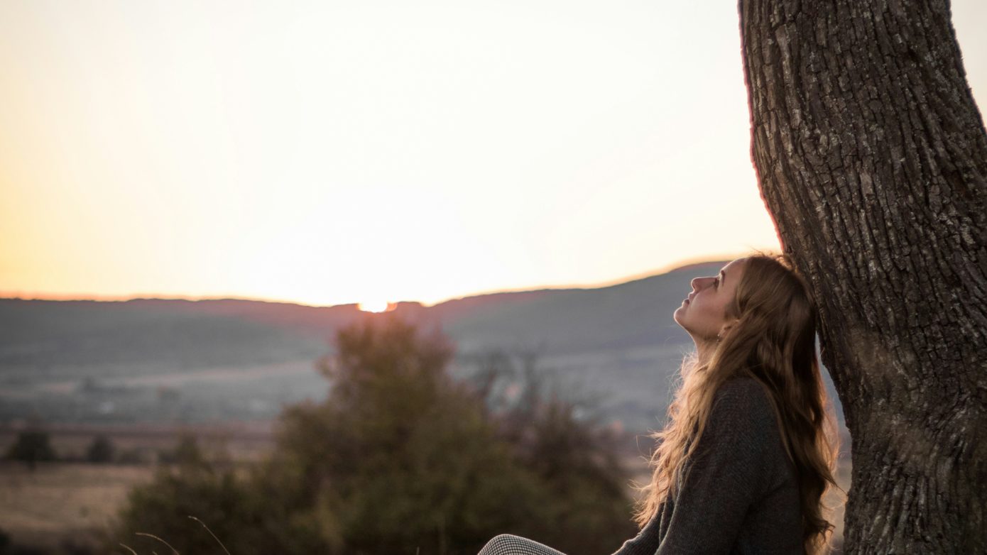 Girl taking in nature under a tree.