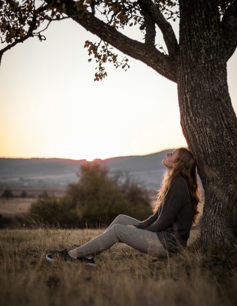 Girl taking in nature under a tree.